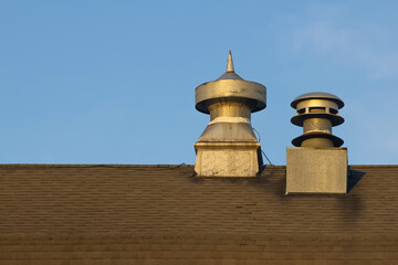 Exterior view of air vent and chimney on a old barn roof against blue background.