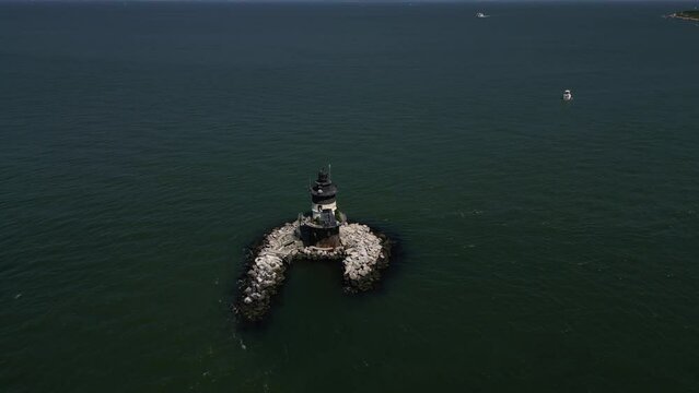 An aerial view the Orient Point lighthouse off the east end of Orient Point, NY on a sunny day. The camera truck right and pan left around the sparkplug lighthouse.