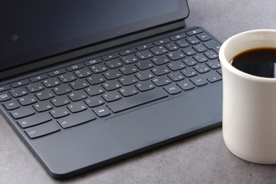 コーヒーを飲みながらノートパソコンでデスクワークをしているイメージ