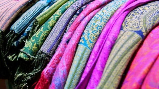 Multi-colored headscarves. Colorful middle eastern shawls. Traditional middle eastern cloth pieces folded at market stall
