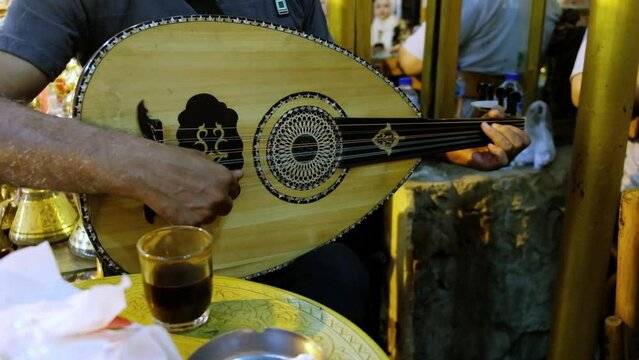 Hands of man playing oud at traditional middle eastern bazaar