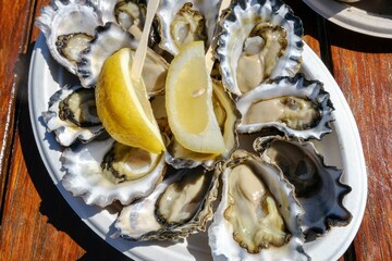 A plate of fresh Sydney rock oysters with lemon wedges on a sunny morning at Jim Wilds Oyster Shack, Greenwell Point, NSW