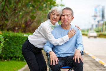 Nature harmony, Asian elderly couple happiness in the outdoor park, Elderly husband on wheelchair, wife caregiving, park outdoor, happy family, grey hair, hug, kiss