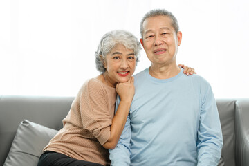Blissful moments, elderly asian husband and wife sharing joy on sofa, timeless romance, heartwarming moments, peaceful harmony, timeless togetherness, happy family couple, grey hair