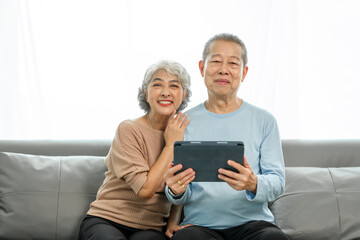 Blissful moments, elderly asian husband and wife sharing joy on sofa, timeless romance, heartwarming moments, peaceful harmony, timeless togetherness, happy family couple, grey hair