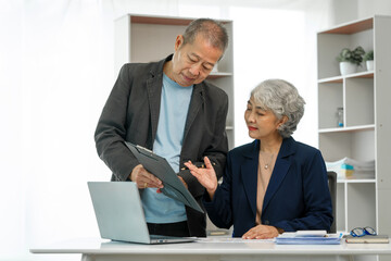 Asian senior man and woman collaborating in small medium enterprises working together.