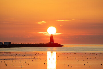 Sun rising directly behind Poolbeg lighthouse in Dublin, Ireland