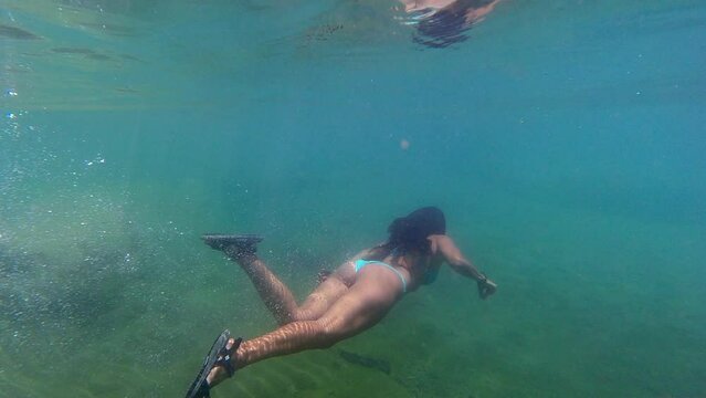 Beautiful woman in bikini swims slo mo underwater in teal river