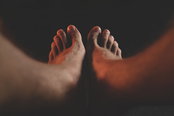 male feet in the dark. Close-up of man's bare feet