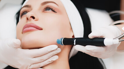 Professional dermatologist in medical gloves doing hydro peeling procedure for beautiful woman...