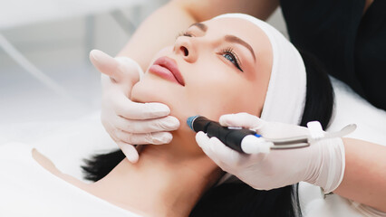 Cosmetologist doing hydrafacial treatment on woman face in beauty clinic