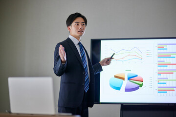 会議室にてプレゼンテーションを行う若い日本人ビジネスマン