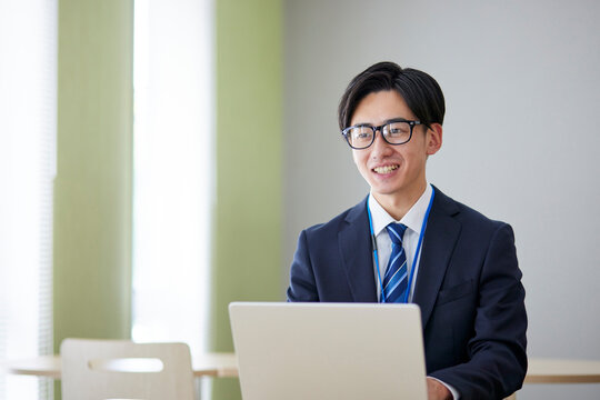 オフィスにてノートパソコンを使用して仕事をする若い日本人ビジネスマン