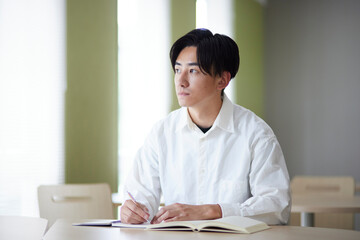 大学の図書室で勉強をする日本人大学生の男性