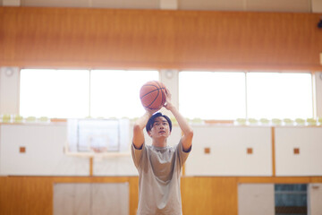 体育館でバスケットボールの練習をする日本人大学生の男性