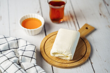 Close up picture of white cream milky kaymak butter roll poured tea on wooden plate.