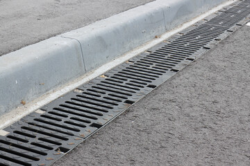 Obraz premium Storm cast-iron grates along the sidewalk curbstone