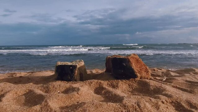Beach and sea, the cinematic camera moves between two rocks on the beach