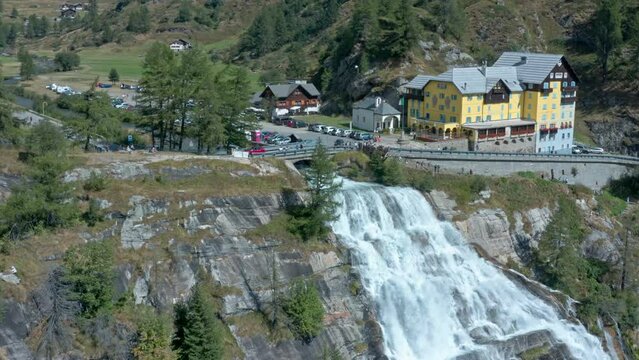 Waterfall cascading down rock face of cliff, Cascata del Toce. Aerial pullback