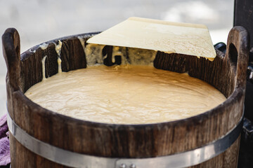 Initial stage of preparation of a tree cake, Lithuanian šakotis, Polish sękacz, Belarusian bankucha, German baumkuchen made of butter, egg whites and yolks, flour, sugar. Ready cream in a wooden bowl