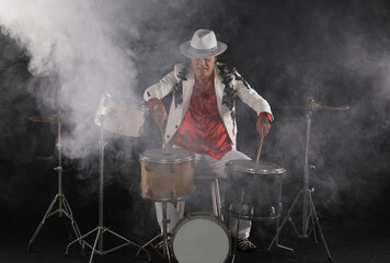Obraz premium male drummer plays drums on a black background