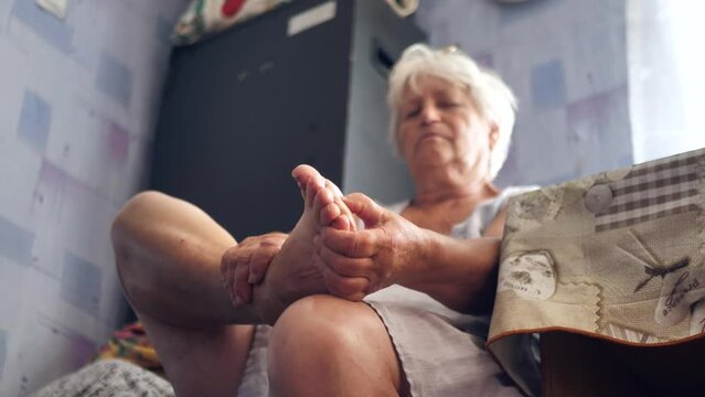 the old woman massages the soles of her feet.
