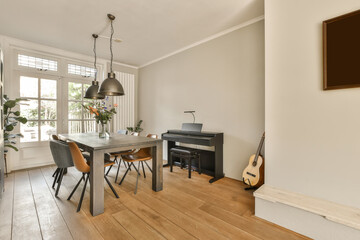 a dining room with wood flooring and white walls there is a piano on the table in front of the window