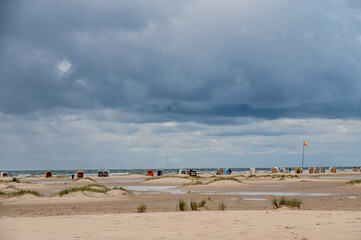 Strandleben am feinen Sandstrand von Norddorf auf der Nordseeinsel Amrum mit dramatischen Wolkenformationen
