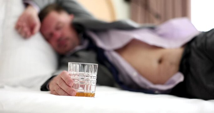 Drunk alcoholic sleeps on bed in shirt. Businessman and alcohol addiction