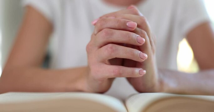 Woman hands are clasped in prayer on bible in church concept of faith spirituality and religion. Woman praying on bible in morning