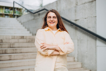 Head shot portrait smart confident smiling millennial woman standing with folded arms on urban...