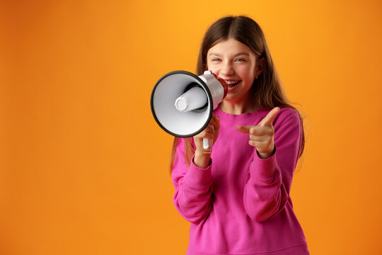 Teen girl making announcement with megaphone on yellow background