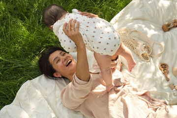 Obraz premium Simple Joys of Life: This photo, capturing a young mother's exuberant play with her baby on a simple grassy lawn, reminds us of the unadulterated happiness found in life's simple moments