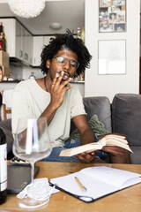 Vintage photo of a young afro boy studying at home while smoking. Vertical photo
