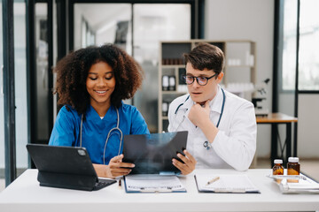 Obraz premium Doctor Talks With Professional Head Nurse or Surgeon, They Use Digital tablet Computer. Diverse Team of Health Care Specialists Discussing Test Result on desk in hospital .