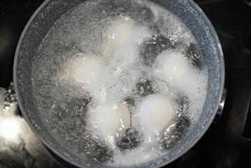Chicken eggs are boiled in a steel pot on the built-in cooker. Boiled egg