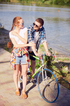 Full length portrait. Smiling woman with her boyfriend enjoying riding a bicycle outdoor wearing summer clothes. Adventure and vacations concept.
