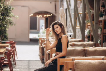 Beautiful blonde model woman, fashionable in a black suit, posing in a cafe