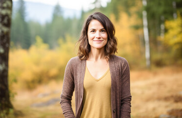 Portrait in the forest of a pleased 30 years old woman. Joyful woman in an  outdoor fall scenery having fun at the autumn season. 