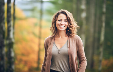 Portrait in the forest of a pleased 30 years old woman. Joyful woman in an  outdoor fall scenery having fun at the autumn season. 