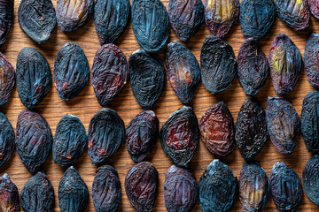 Sun dried pitted plums on a wooden table, closeup, top view. Background and texture of dried raw plums
