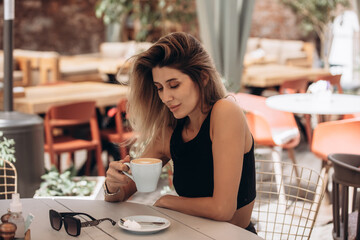 Beautiful blonde model woman, fashionable in a black suit, posing in a cafe