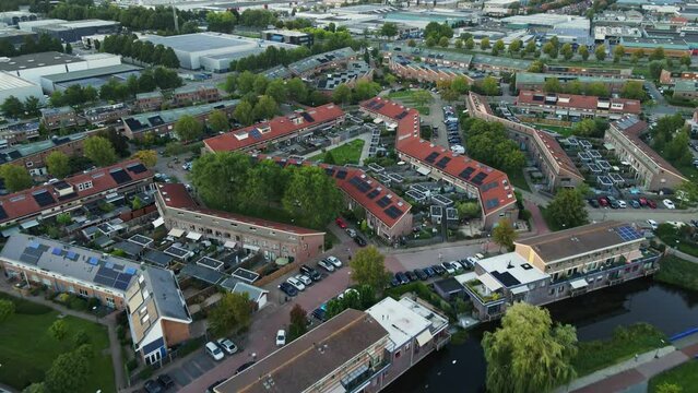 Aerial of a beautiful suburban neighborhood in the Netherlands. The drone flies backwards and reveals a river and a green park
