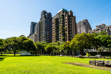 Obraz premium Low-angle view of green park space and modern buildings on both sides in downtown Taichung, Taiwan, It is near the National Taichung Theater.