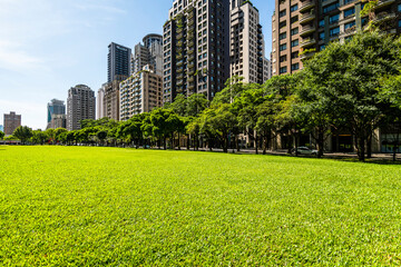 Low-angle view of green park space and modern buildings on both sides in downtown Taichung, Taiwan....