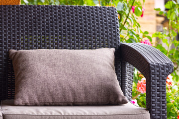Close-up of pillow on rattan sofa, terrace, relaxation at home. - obrazy, fototapety, plakaty