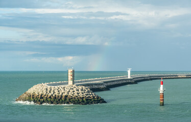 Harbor entrance in Calais, France with a rainbow
