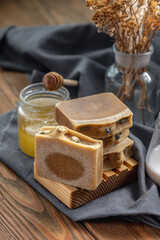 Fototapeta na wymiar Pieces of natural honey soap handmade on a wooden soap dish. Beautiful atmospheric postcard