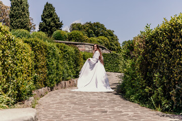 Brunette runs white dress park. A beautiful woman with long brown hair and a long white dress runs...