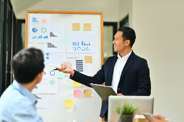 Professional businessman giving presentation, explaining report investment graph chart data in meeting room